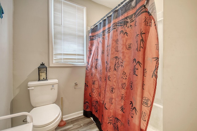 bathroom with hardwood / wood-style flooring, toilet, and shower / tub combo