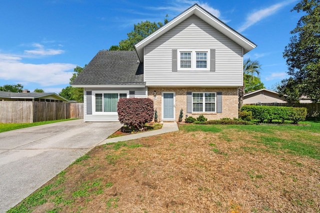 view of front of house featuring roof with shingles, fence, a front lawn, brick siding, and driveway