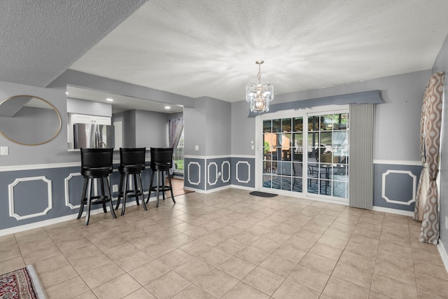dining area with an inviting chandelier, wainscoting, and a textured ceiling
