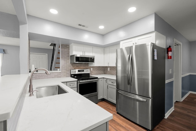 kitchen with tasteful backsplash, visible vents, a sink, dark wood-style flooring, and stainless steel appliances