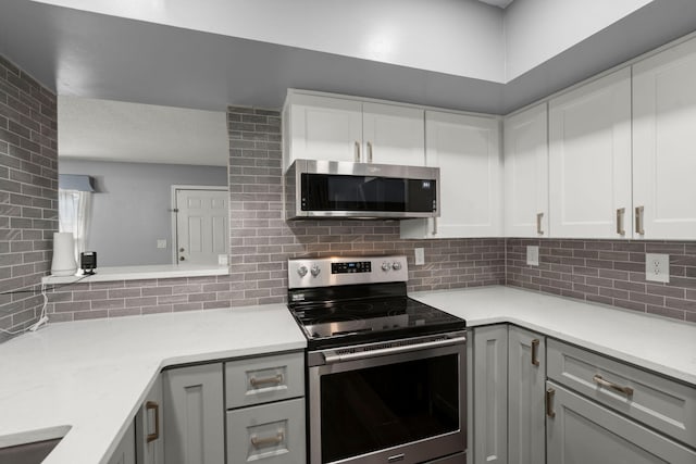 kitchen with backsplash, gray cabinets, appliances with stainless steel finishes, and light countertops