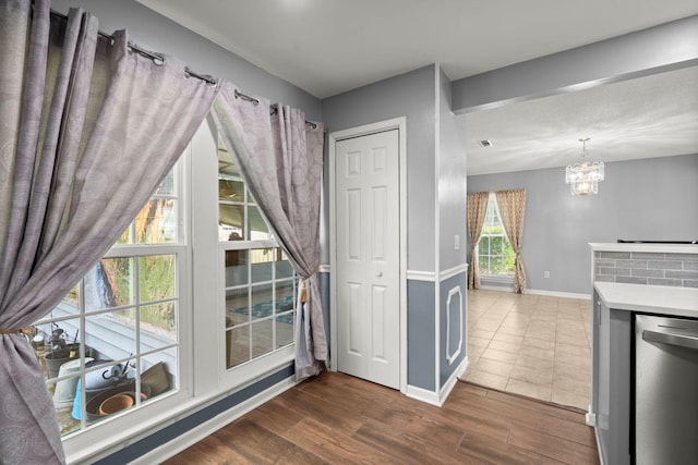 interior space with dark wood-type flooring, a notable chandelier, and baseboards