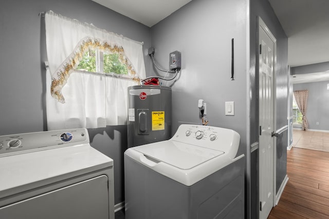 clothes washing area featuring laundry area, a wealth of natural light, wood finished floors, electric water heater, and washer and dryer