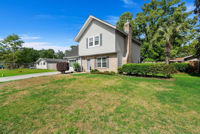 view of front of home featuring brick siding, a front yard, and a chimney