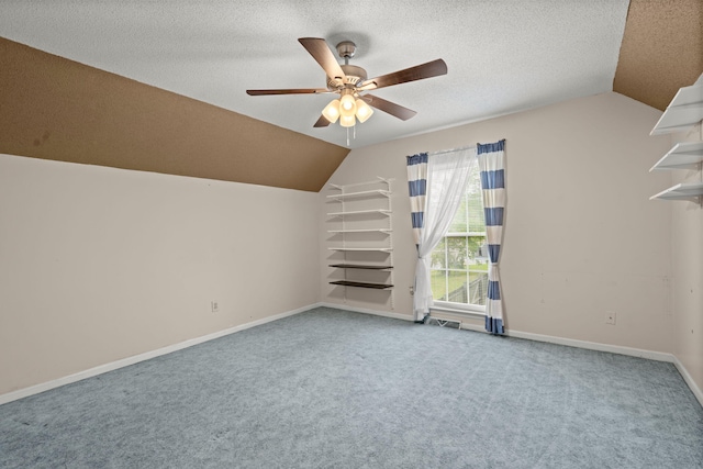 additional living space featuring baseboards, vaulted ceiling, a textured ceiling, carpet floors, and ceiling fan