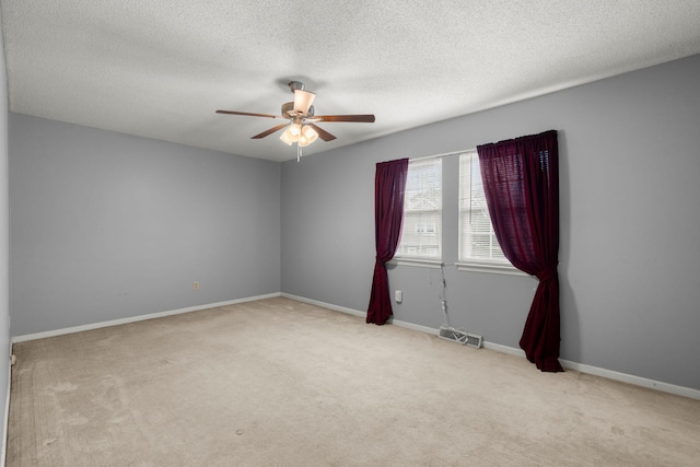 empty room featuring carpet, a textured ceiling, baseboards, and ceiling fan