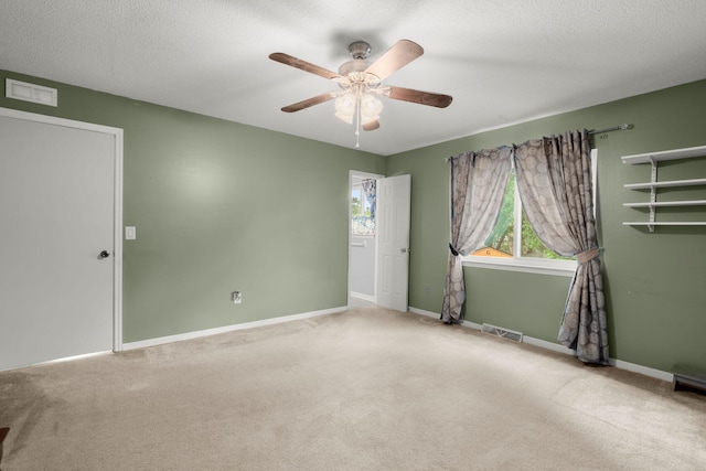 carpeted spare room with visible vents, baseboards, and a ceiling fan