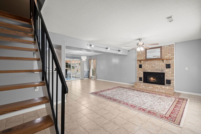 unfurnished living room with visible vents, a brick fireplace, a ceiling fan, a textured ceiling, and tile patterned floors