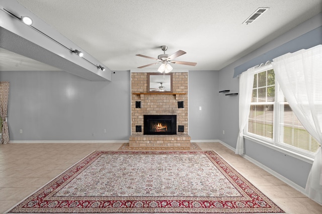 unfurnished living room with visible vents, light tile patterned floors, ceiling fan, a fireplace, and a textured ceiling