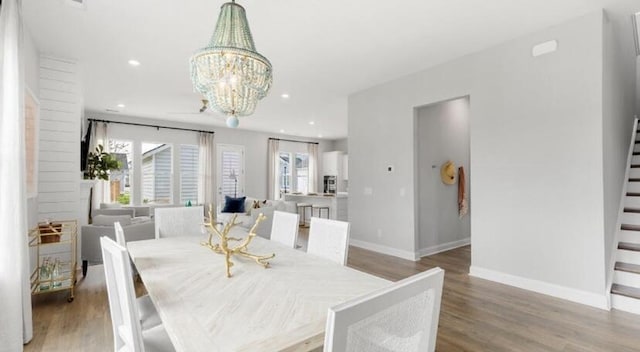 dining room featuring stairs, baseboards, a notable chandelier, and wood finished floors