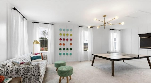 rec room featuring a notable chandelier, a healthy amount of sunlight, and light carpet