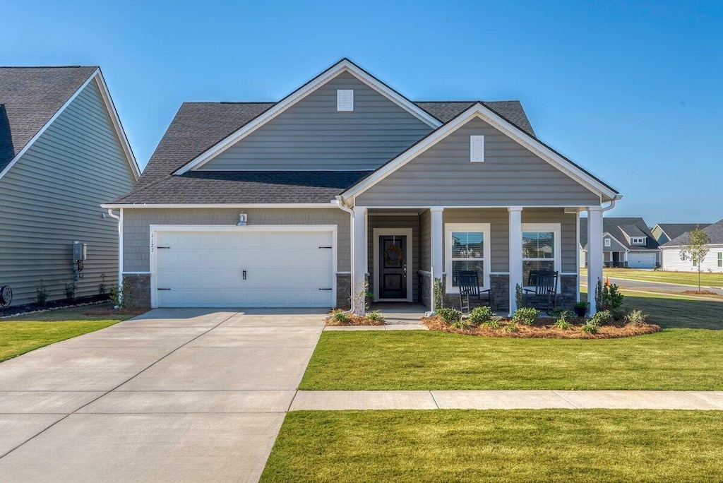 craftsman-style home with a porch, a garage, and a front lawn