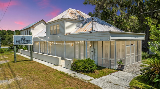 view of front of house with a lawn and a sunroom