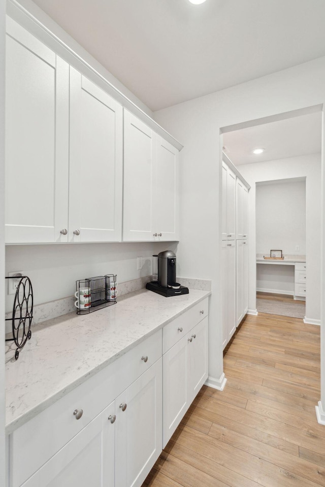 kitchen featuring light stone counters, light hardwood / wood-style flooring, and white cabinets