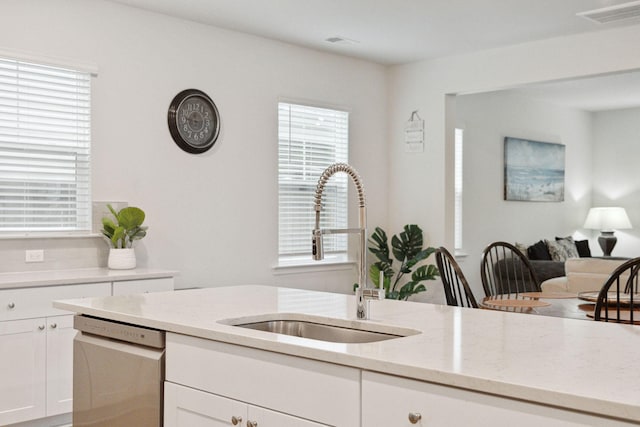 kitchen with white cabinetry, dishwasher, light stone countertops, and sink