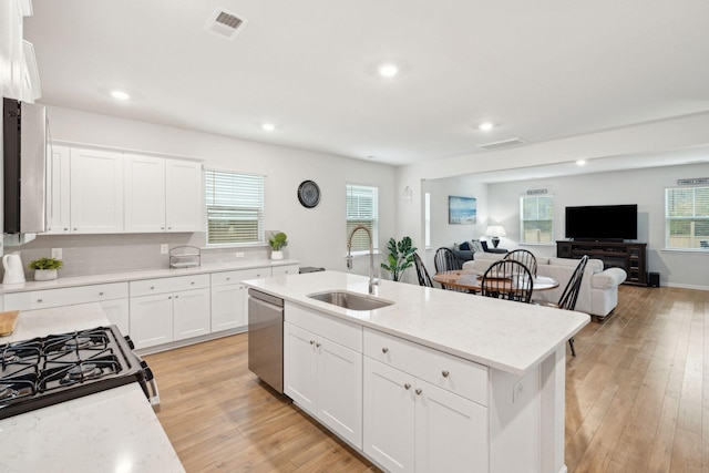 kitchen featuring white cabinets, dishwasher, sink, and a kitchen island with sink