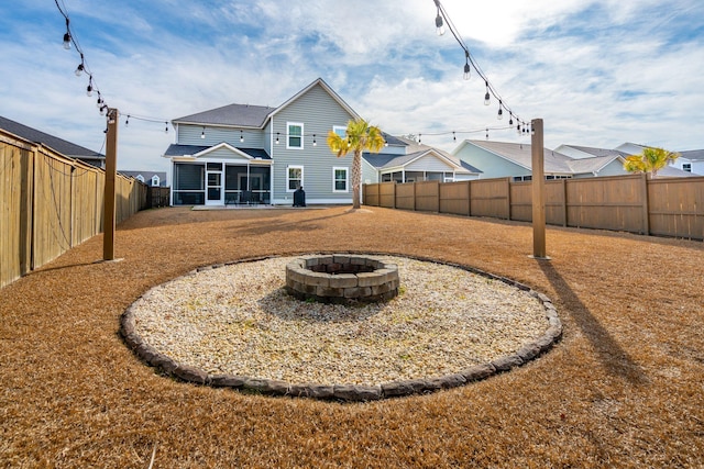 back of property with an outdoor fire pit and a sunroom