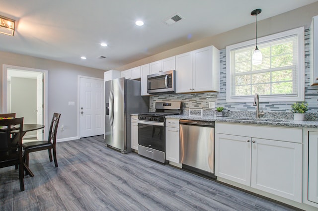 kitchen featuring stainless steel appliances, light hardwood / wood-style floors, white cabinetry, sink, and tasteful backsplash