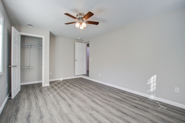 unfurnished bedroom featuring ceiling fan, a closet, and wood-type flooring