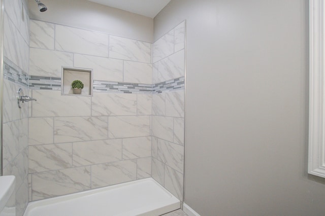 bathroom featuring toilet and a tile shower