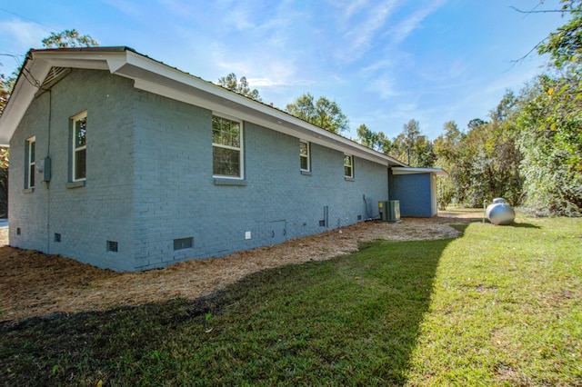 view of side of home with central AC and a yard