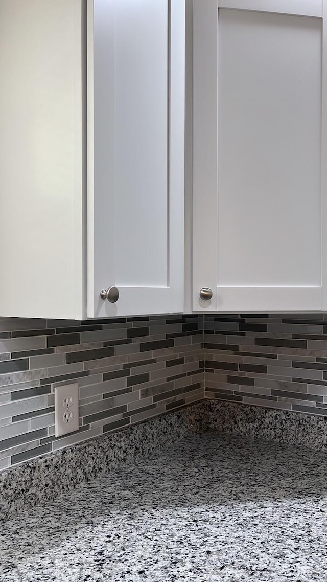 room details featuring white cabinetry, tasteful backsplash, and light stone countertops