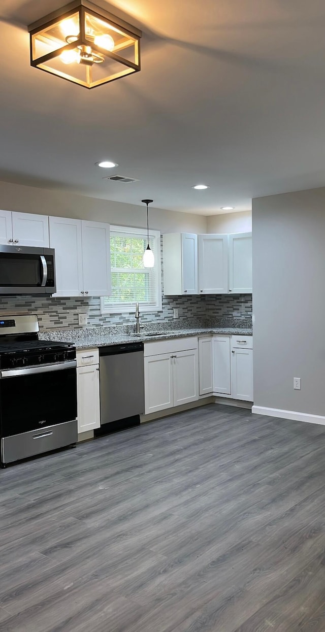 kitchen featuring stainless steel appliances, backsplash, dark hardwood / wood-style floors, pendant lighting, and white cabinets