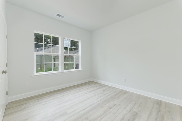 unfurnished room with visible vents, wood finished floors, and baseboards