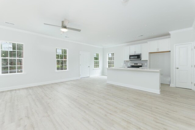 kitchen with plenty of natural light, an island with sink, stainless steel appliances, and ceiling fan