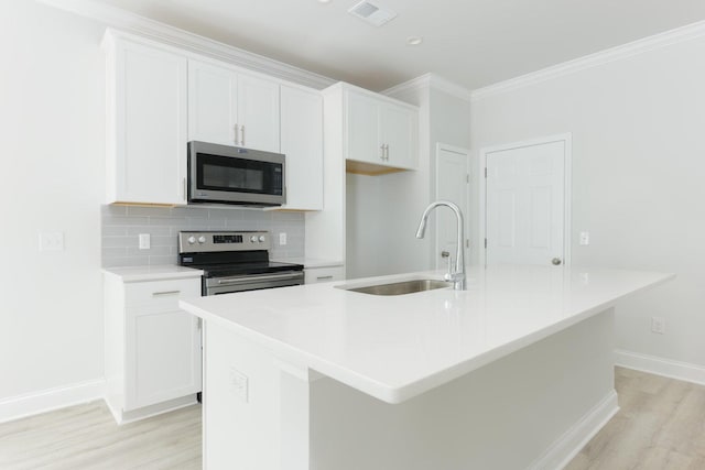 kitchen with light wood-type flooring, sink, appliances with stainless steel finishes, and a kitchen island with sink