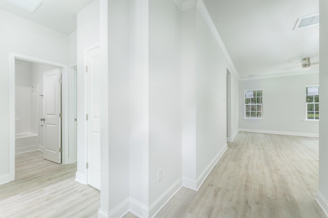 corridor featuring visible vents, baseboards, crown molding, and light wood-style floors