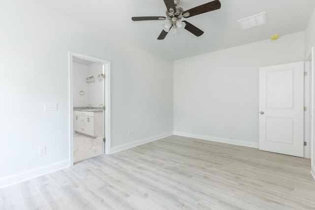 unfurnished bedroom featuring light wood finished floors, visible vents, baseboards, ensuite bathroom, and a sink