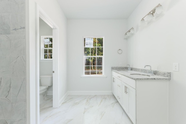 bathroom featuring marble finish floor, toilet, baseboards, and a sink