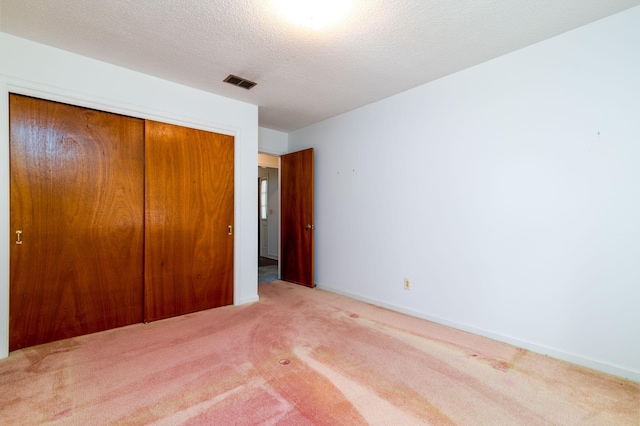 unfurnished bedroom with light carpet, a textured ceiling, and a closet