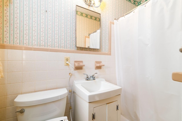 bathroom featuring vanity, toilet, and tile walls