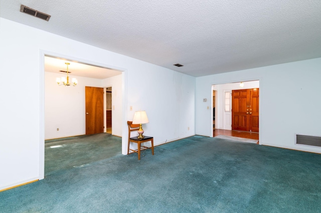 spare room with dark carpet, a textured ceiling, and a chandelier