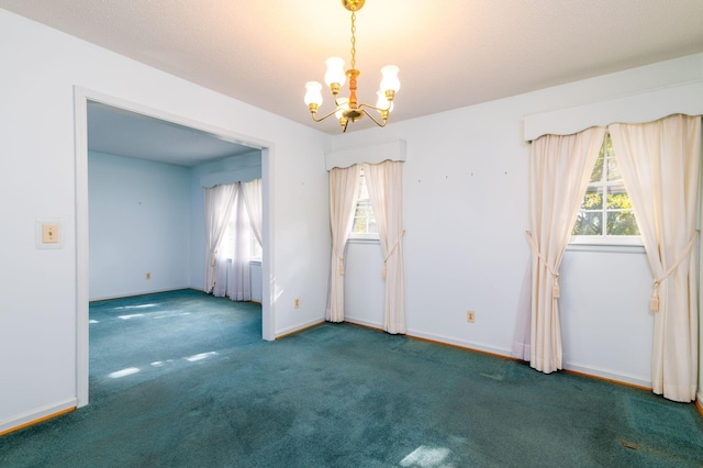 carpeted spare room featuring plenty of natural light and a chandelier