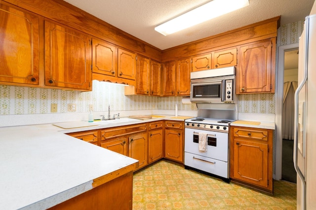 kitchen featuring a textured ceiling, sink, and white appliances