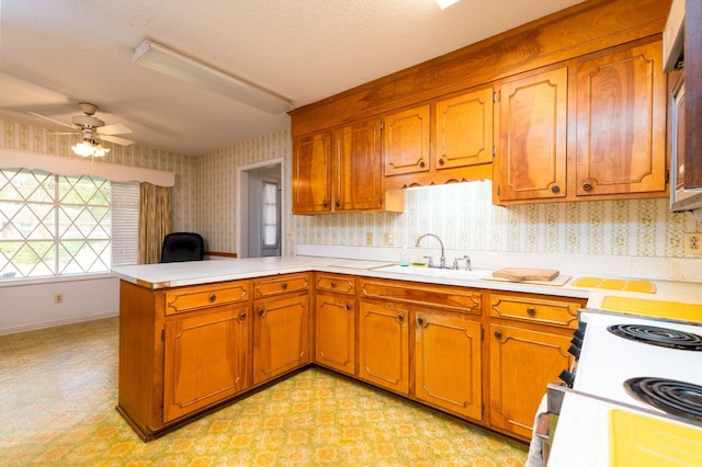 kitchen with sink, ceiling fan, a textured ceiling, white range with electric stovetop, and kitchen peninsula