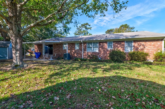 back of property with a lawn, a patio, and a shed