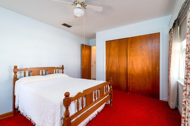 carpeted bedroom featuring ceiling fan, a closet, and a textured ceiling