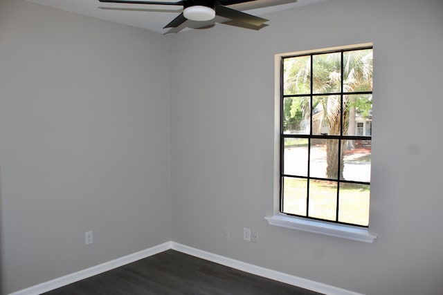 spare room with a ceiling fan, dark wood finished floors, healthy amount of natural light, and baseboards
