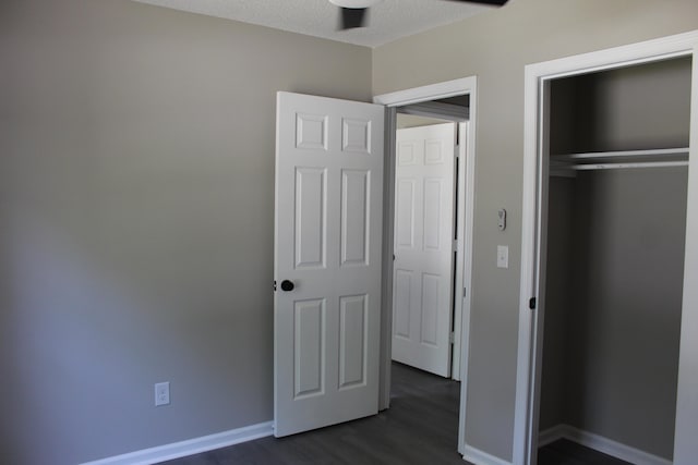 unfurnished bedroom featuring dark wood-style flooring, baseboards, and a closet