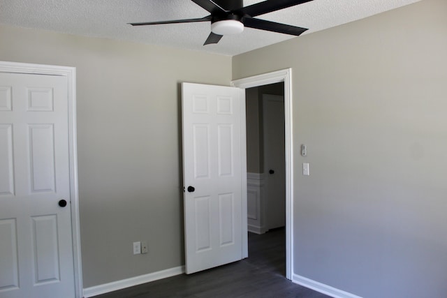 unfurnished bedroom with dark wood-style floors, baseboards, a textured ceiling, and a ceiling fan