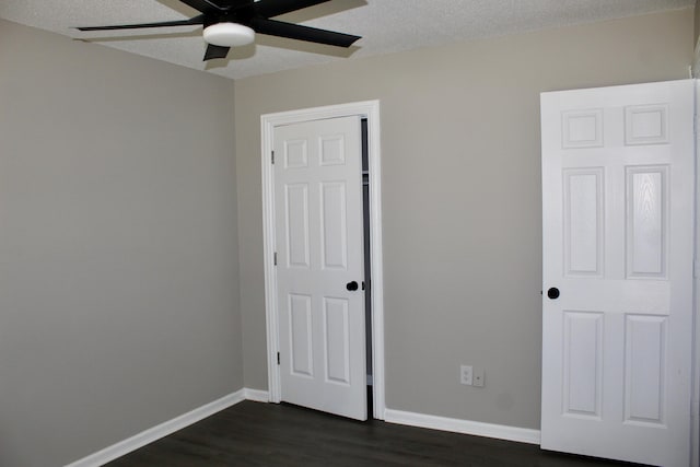 unfurnished bedroom with dark wood-style floors, baseboards, a textured ceiling, ceiling fan, and a closet