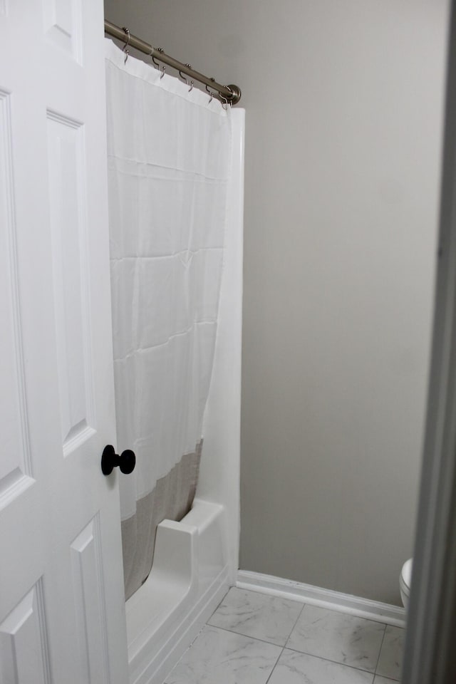 full bath featuring marble look tiles, baseboards, a shower with shower curtain, and toilet