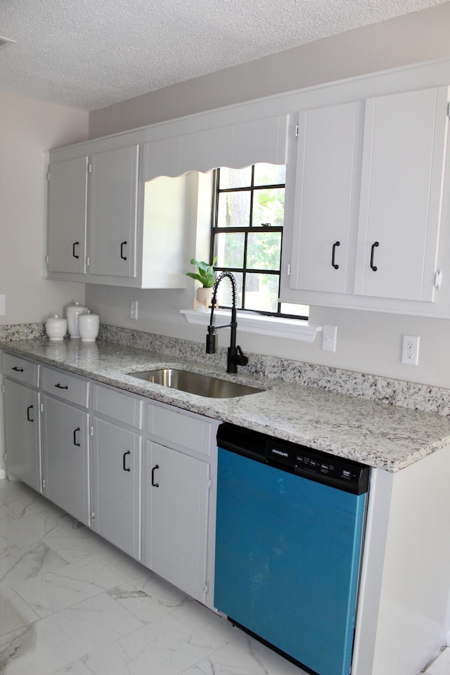 kitchen featuring dishwasher, a sink, light marble finish floors, and a textured ceiling