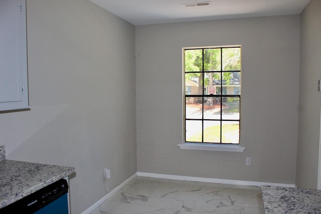 unfurnished dining area with light marble finish flooring and baseboards