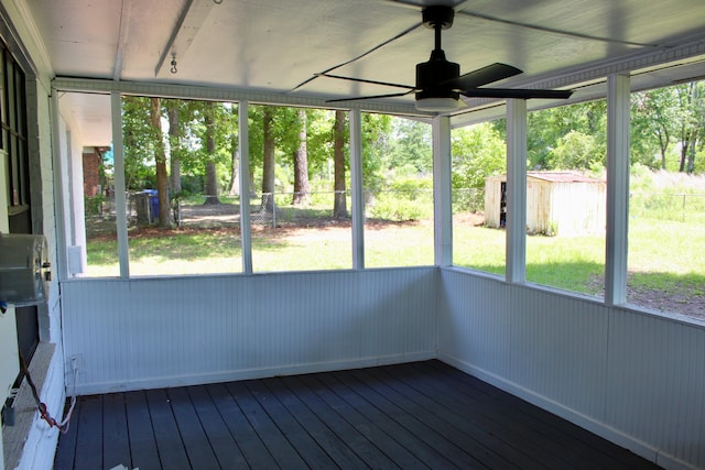 unfurnished sunroom featuring a ceiling fan and plenty of natural light