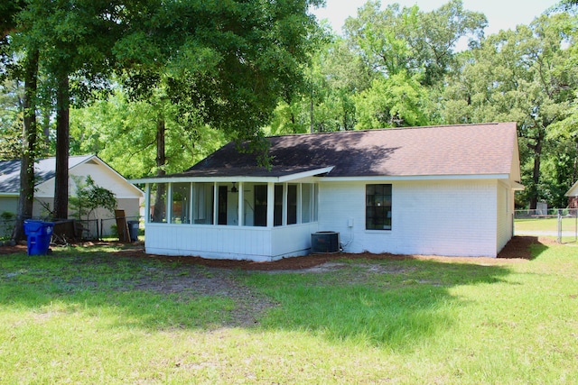 back of property with a sunroom, a shingled roof, cooling unit, and brick siding
